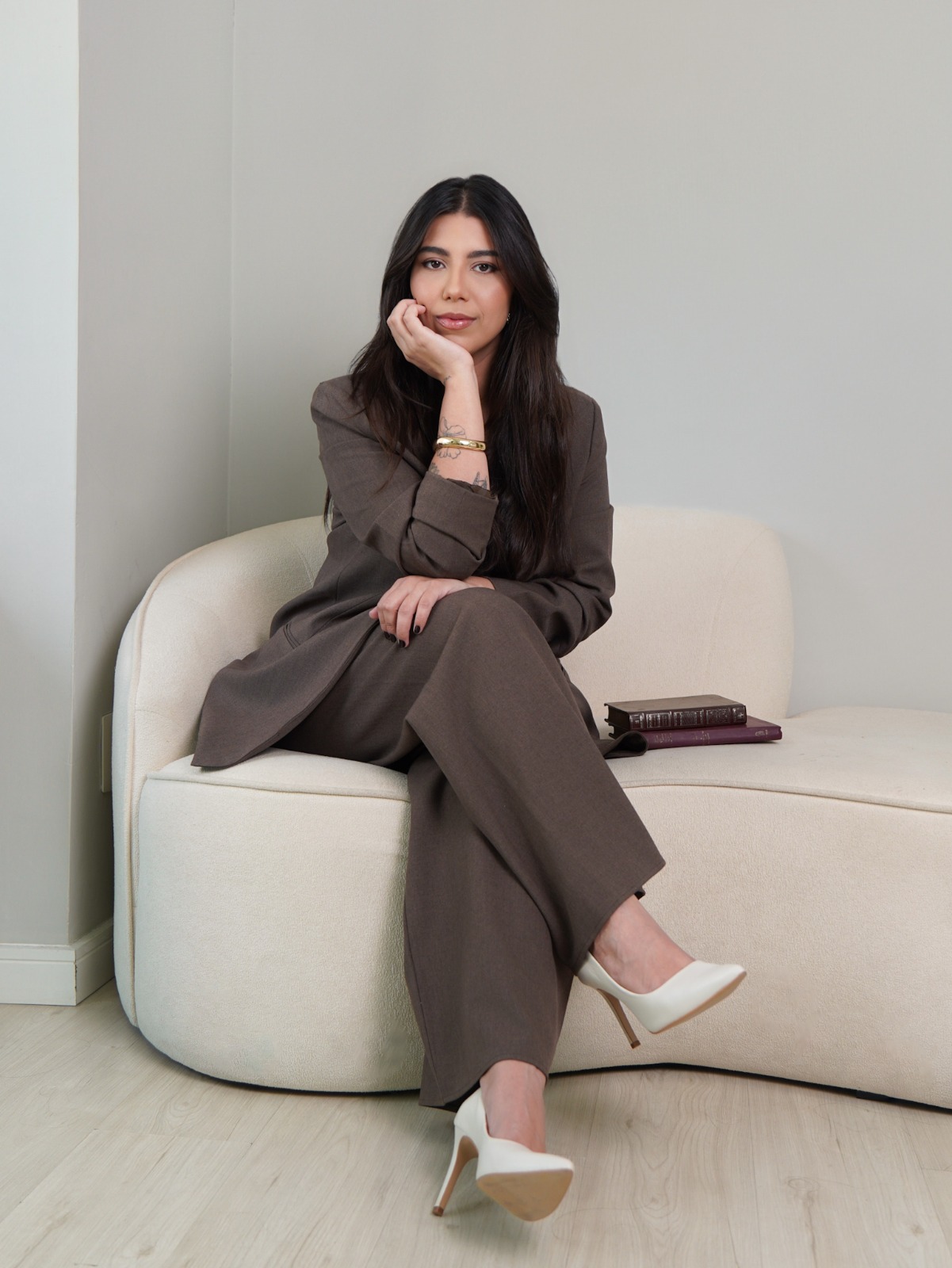 Retrato profissional de Lorena Cirino, psicóloga clínica, sentada em um sofá claro